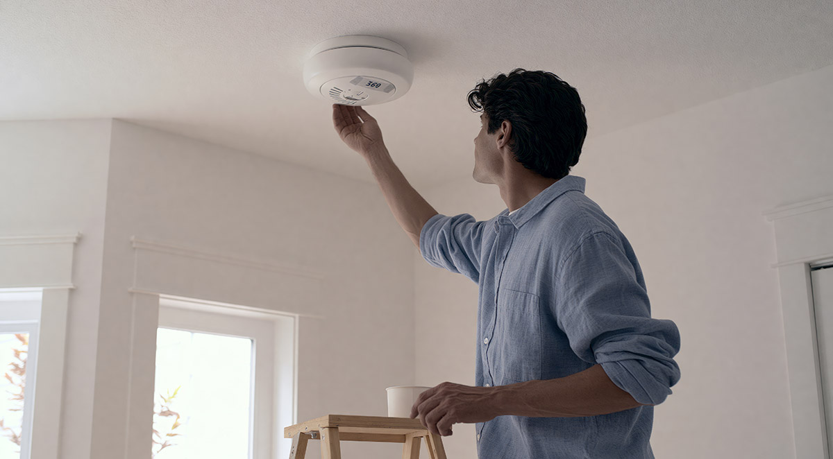 property inspector checking smoke alarm replacement date ceiling